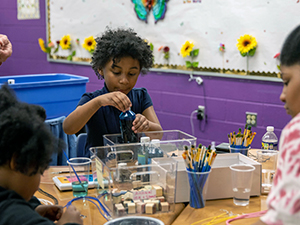 Student working on art project with other students